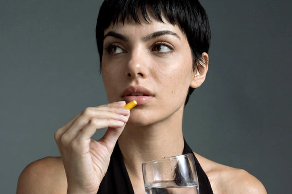 Imagem de uma mulher a segurar uma cápsula de Curcuma Aldous.