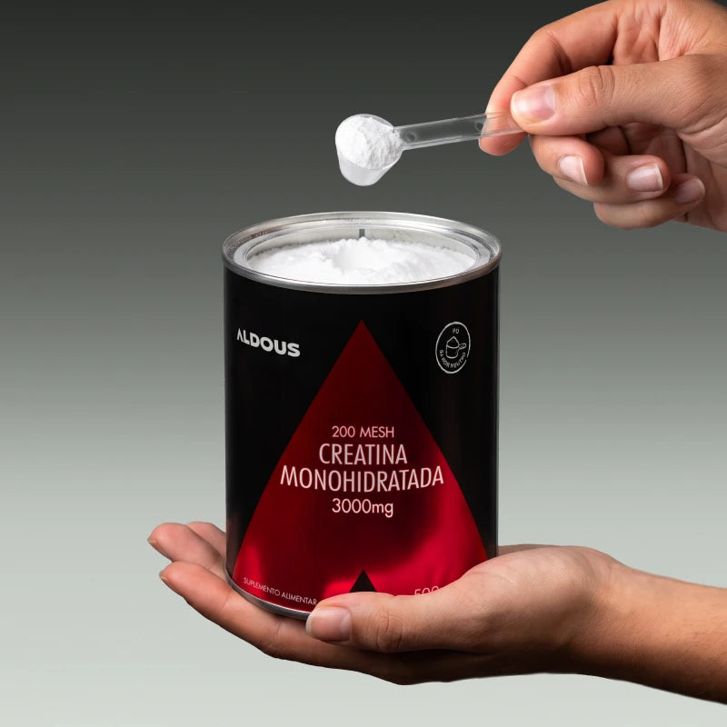 Imagem de umas mãos a retirar uma colher de creatina do frasco de Creatina Aldous